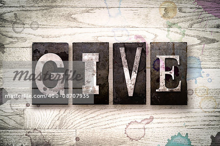 The word "GIVE" written in vintage dirty metal letterpress type on a whitewashed wooden background with ink and paint stains.
