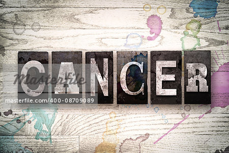 The word "CANCER" written in vintage, dirty metal letterpress type on a whitewashed wooden background with ink and paint stains.