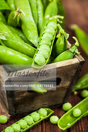 Fresh ripe green peas in wooden box