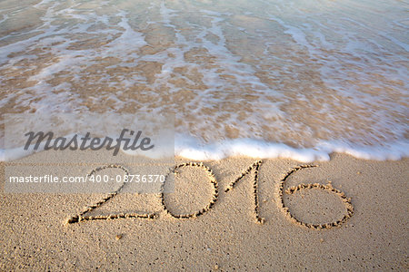 Inscription 2016 on a beach sand, the wave is almost covering the digits 2016.