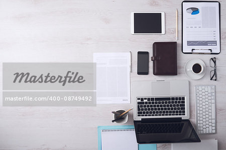 Businessman tidy desktop with laptop, tablet, smartphone, financial reports and various objects, copyspace on the left, top view
