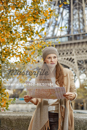 Autumn getaways in Paris. young tourist woman on embankment in Paris, France with map