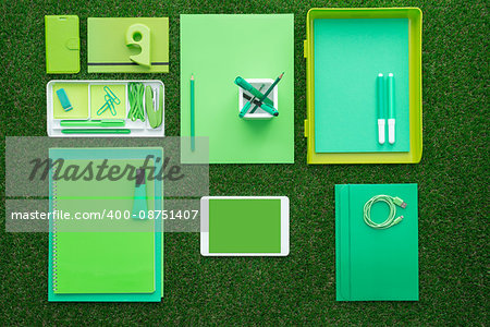 Green office supplies and digital touch screen tablet on the grass, business and ecology concept