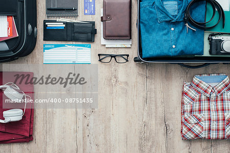 Getting ready for a trip and packing a suitcase before leaving; accessories, clothing and personal items on a desktop, travel and vacations concept