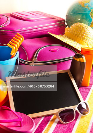 Empty blackboard with summer holidays background, including sunglasses, sun cream and bag.