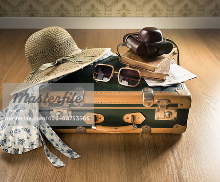 Vintage traveler suitcase with sunglasses, straw hat, old camera and maps.
