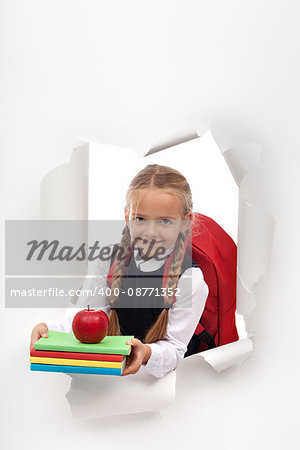 Enthusiastic little schoolgirl ready for school - bursting out from a white paper layer, copy space
