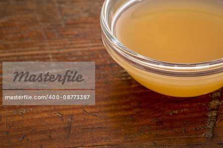 unfiltered, raw apple cider vinegar with mother  - a small glass bowl against rustic wood with a copy space