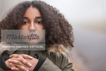 Beautiful mixed race African American girl teenager female young woman outside in autumn or fall mist or fog looking sad depressed or thoughtful