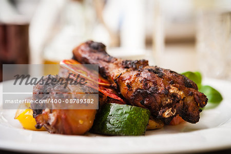 Red Orange glazed chicken with grilled vegetables served on a white plate