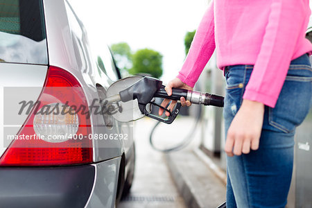 Closeup of woman pumping gasoline fuel in car at gas station. Petrol or gasoline being pumped into a motor vehicle car.