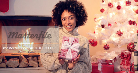 Close up of beautiful black woman holding present while seated by fireplace