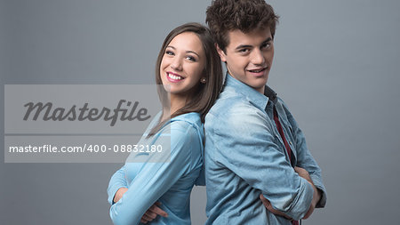 Young happy couple back to back smiling at camera