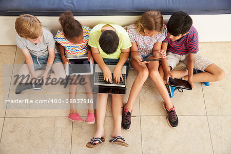 Overhead Shot Of Children Sitting On Floor Using Technology