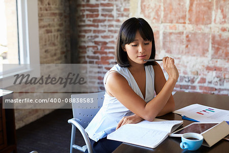 Businesswoman Making Notes On Document In Boardroom