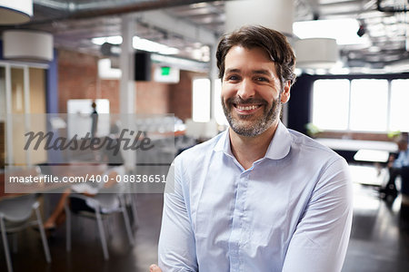 Portrait Of Businessman In Modern Open Plan Office