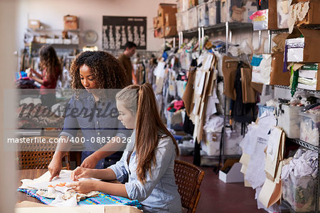 Woman stands to train an apprentice at clothes design studio