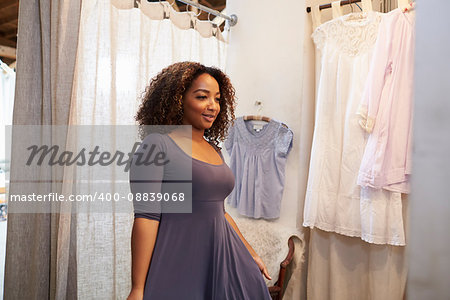 Woman trying on a dress in a boutique changing room