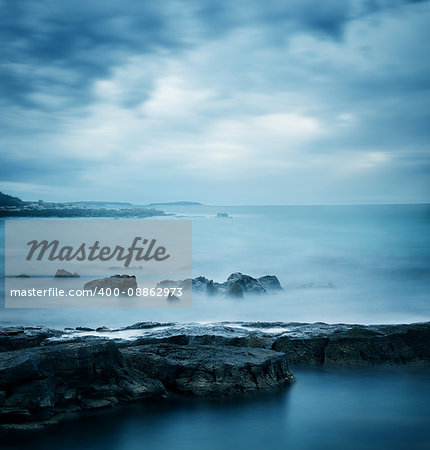 Peaceful Winter Seascape. Sea or Ocean with Dramatic Sky. Long Exposure. Calm Water and Moody Sky. Cold Mysterious Tranquility Concept. Blue Toned Photo with Copyspace.