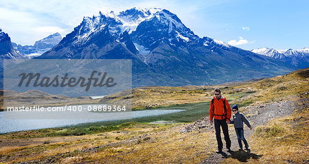 family of two, father and son, enjoying hiking and active travel in torres del paine national park in patagonia, chile, view of cuernos del paine