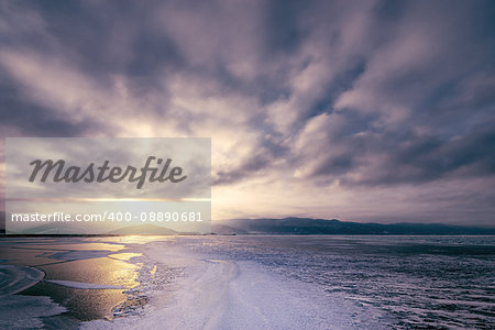 Frozen surface of Baikal lake at sunset. Russia.