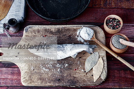 Fresh fish smelt spices for cooking on a kitchen board, a number of spices and frying pan