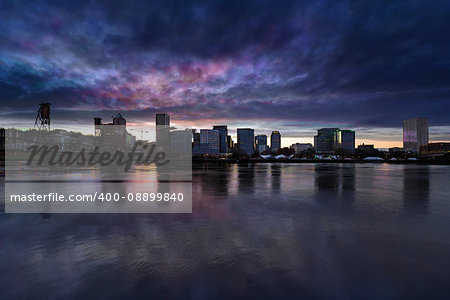 Portland Oregon downtown city skyline from Eastbank Esplanade along Willamette River waterfront during cloudy twilight evening