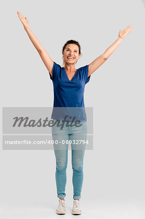 Portrait of a happy middle aged brunette with arms up