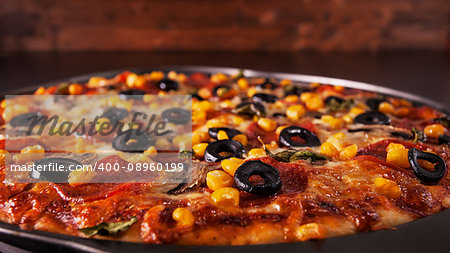 Freshly baked delicious pizza in baking pan - closeup with copy space above, low key