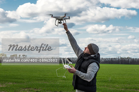 man holding of flying drone quadrocopter at the green field.