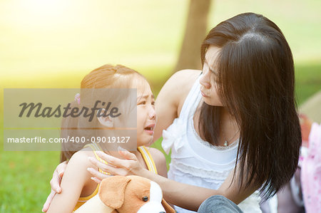 Portrait of Asian mother comforting her crying daughter in the park, Family outdoor lifestyle.