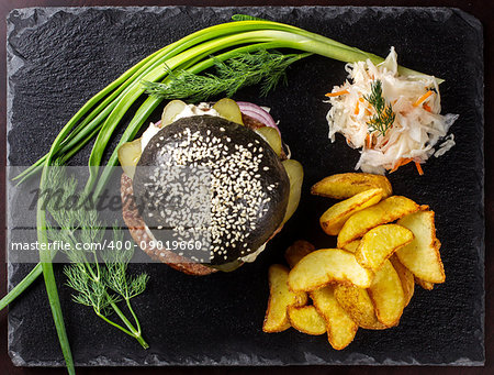Black hamburger on stone table with black background. Fastfood meal. Delicious Hamburger. Top view.