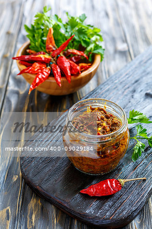 Hot pepper sauce in glass jar on old wooden table, selective focus.