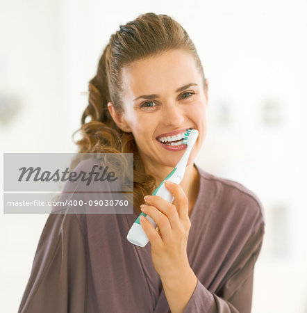 Happy young woman brushing teeth in bathroom