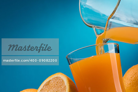 Pouring orange juice into a glass and sliced fresh oranges, vitamins and healthy drinks concept