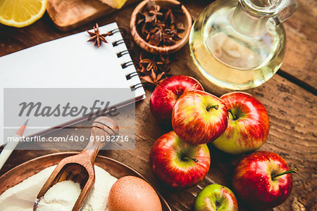 Baking background with paper for notes. Christmas and winter  cookies ingredients.Baking pastry and cookies: apples, spices, sugar, eggs on wood