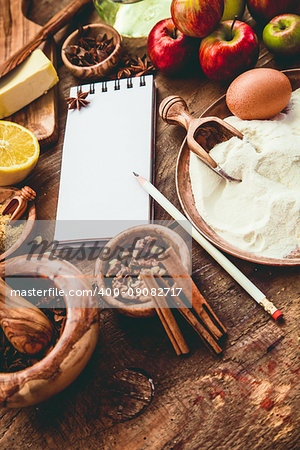 Baking background with paper for notes. Christmas and winter  cookies ingredients.Baking pastry and cookies: apples, spices, sugar, eggs on wood