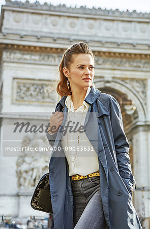 Stylish autumn in Paris. young woman in trench coat near Arc de Triomphe in Paris, France looking aside
