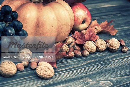 Pumpkin, apple, nuts, berries with maple leaves on wooden background. Autumn card thanksgiving. Halloween. Vintage toned