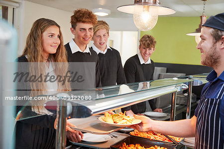 Teenage Students Being Served Meal In School Canteen