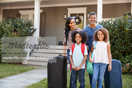 Portrait Of Family With Luggage Leaving House For Vacation