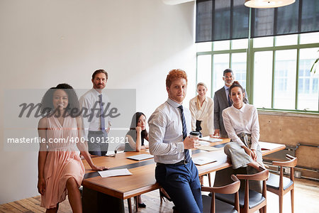 Young professionals in a meeting room looking to camera