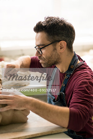 Ceramist Dressed in an Apron Sculpting Statue from Raw Clay in the Bright Ceramic Workshop.