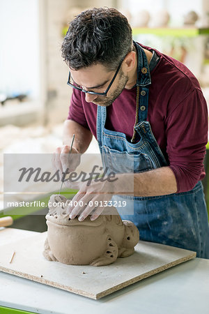 Ceramist Dressed in an Apron Sculpting Statue from Raw Clay in the Bright Ceramic Workshop.