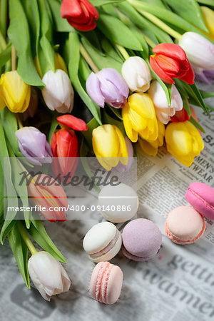 Colorful macaroons and tulips on newspaper