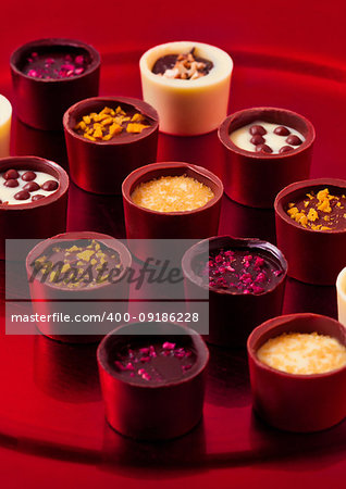 Assortment of luxury white and dark chocolate candies variety on red plate