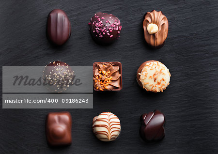 Assortment of luxury white and dark chocolate candies variety on black stone background