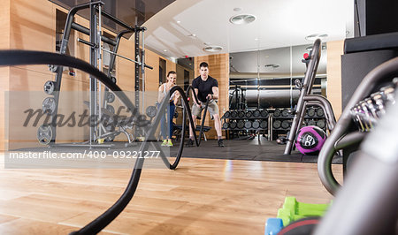 Low-angle view of a young determined man waving battle ropes with alternative motion during an intense session of functional training in the gym
