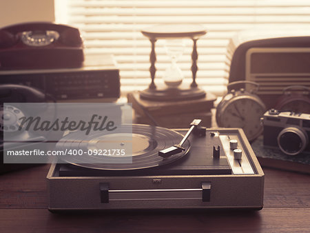 Vintage retro revival objects and appliances assortment on a table, turntable record player on the foreground