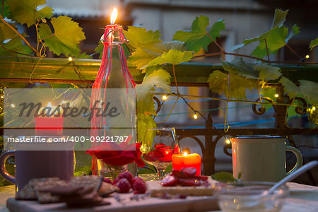 Candles on romantic table with sweets at late evening